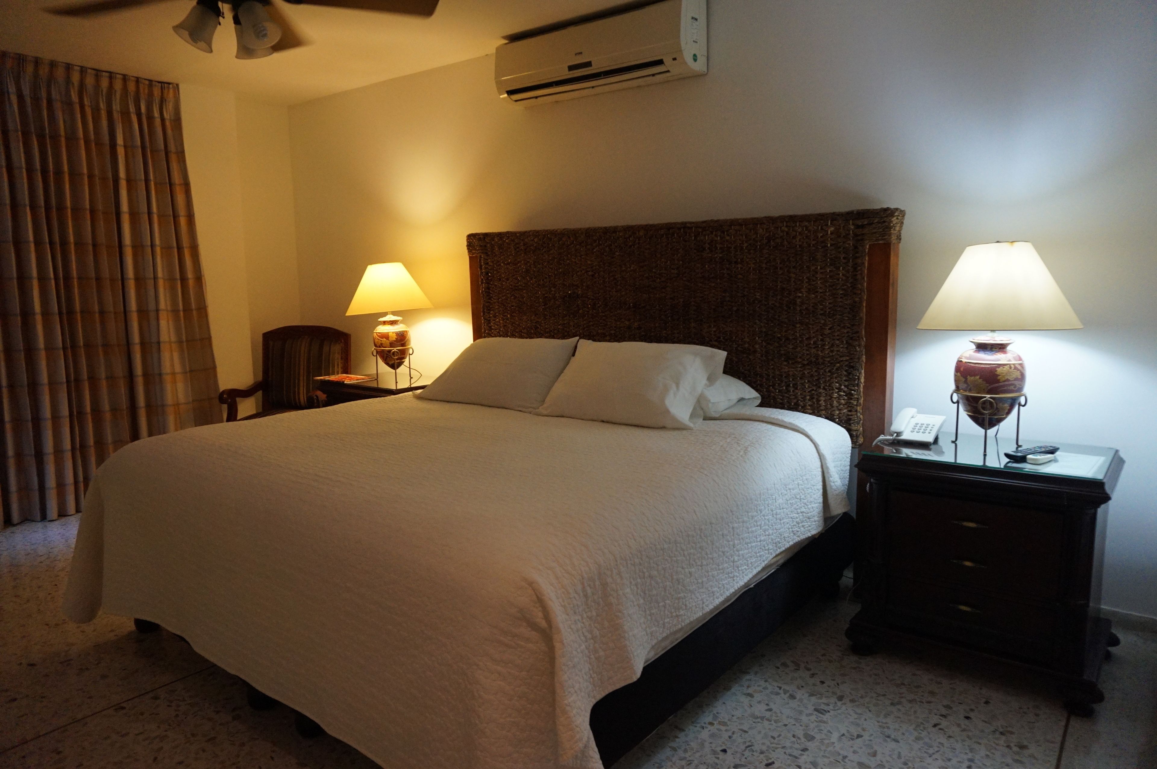 Une chambre d’hôtel avec un grand lit, deux lampes de chevet, un téléphone et un appareil de climatisation fixé au mur.