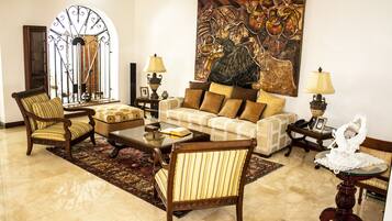 Un salón amplio con un sofá grande, sillones, una mesa de centro y un cuadro decorativo en la pared.