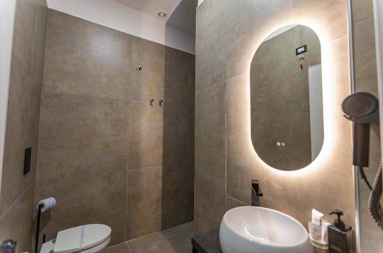 Un bagno moderno con uno specchio grande, un water e un lavandino.