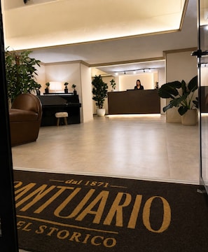 A reception area with a receptionist, a piano, and potted plants.