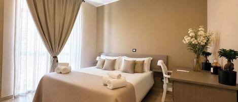 A hotel room with a large bed, a desk, and a chair.