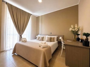 Quarto de hotel com uma cama grande, uma escrivaninha e uma cadeira.