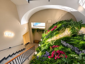 A staircase with a railing, a wall with greenery, and a window.