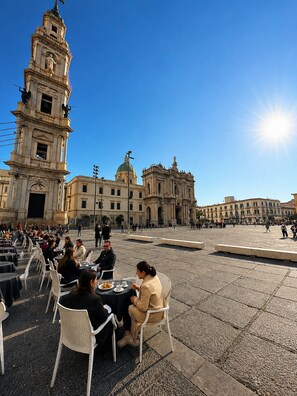 A plaza with outdoor seating, a prominent clock tower, and classical architecture. - Hotel Santuario Pompei (Pompei)