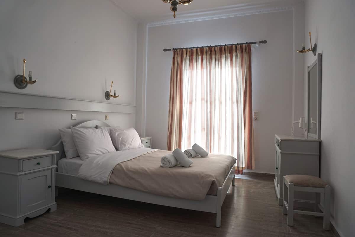 A bedroom with a bed, nightstands, a chair, and a mirror.