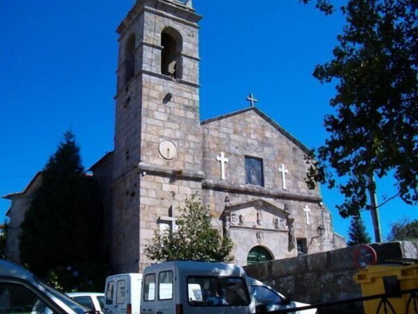 A church with a tall bell tower and a cross on top.