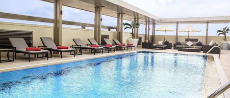 A rooftop pool area with sun loungers and a pool.