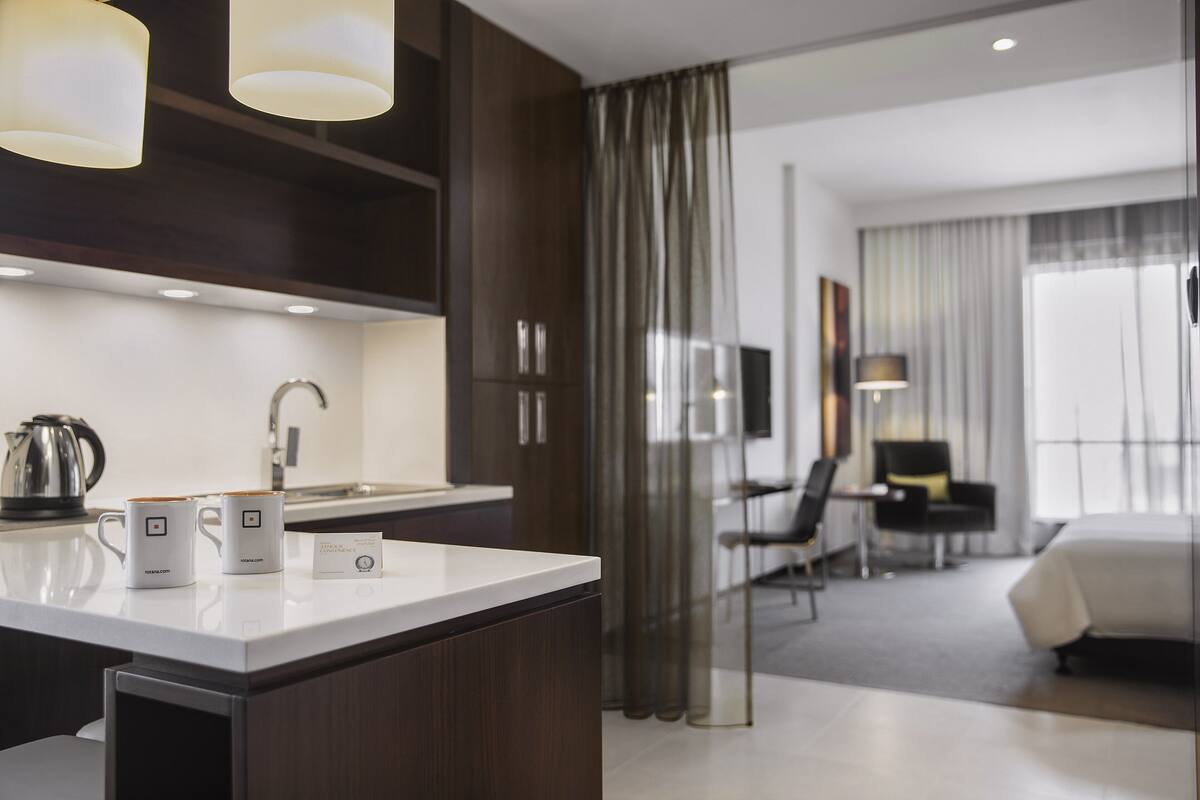 Une chambre d’hôtel moderne dotée d’un coin cuisine, d’une table à manger et d’une chambre à coucher séparée.