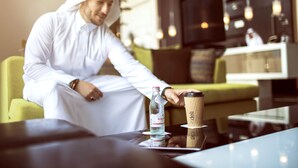 A man in traditional attire sitting at a table with a bottle of water and a coffee cup. - Centro Shaheen Jeddah by Rotana (Jeddah)
