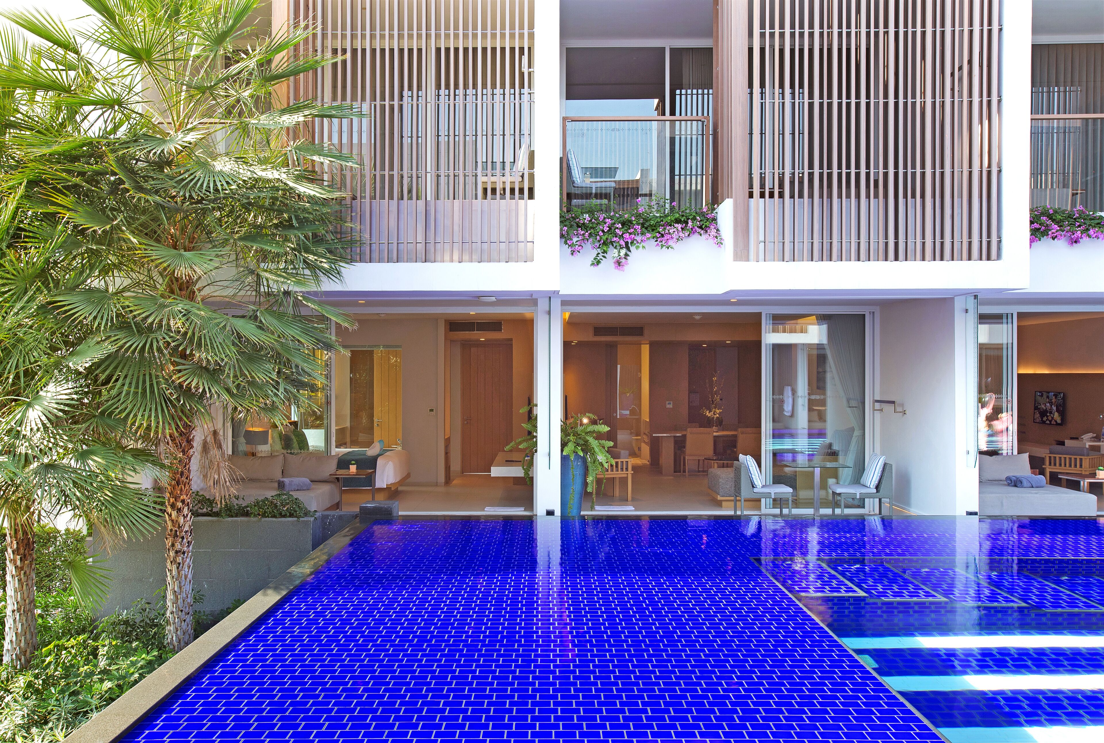 A modern building with a rooftop pool, outdoor seating, and a well-maintained garden.