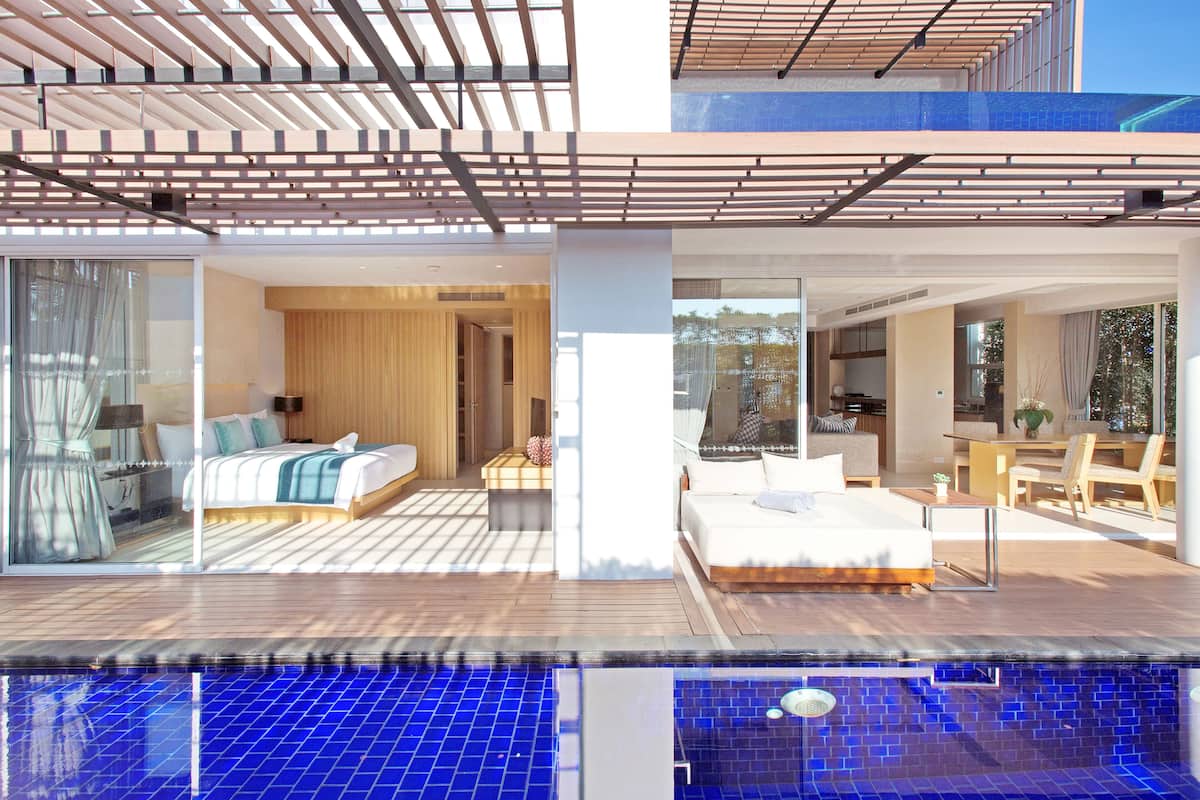 Ein modernes Hotel mit großem Pool, einem Schlafzimmer mit großem Bett sowie einem Badezimmer und einem Essbereich mit Tisch und Stühlen.