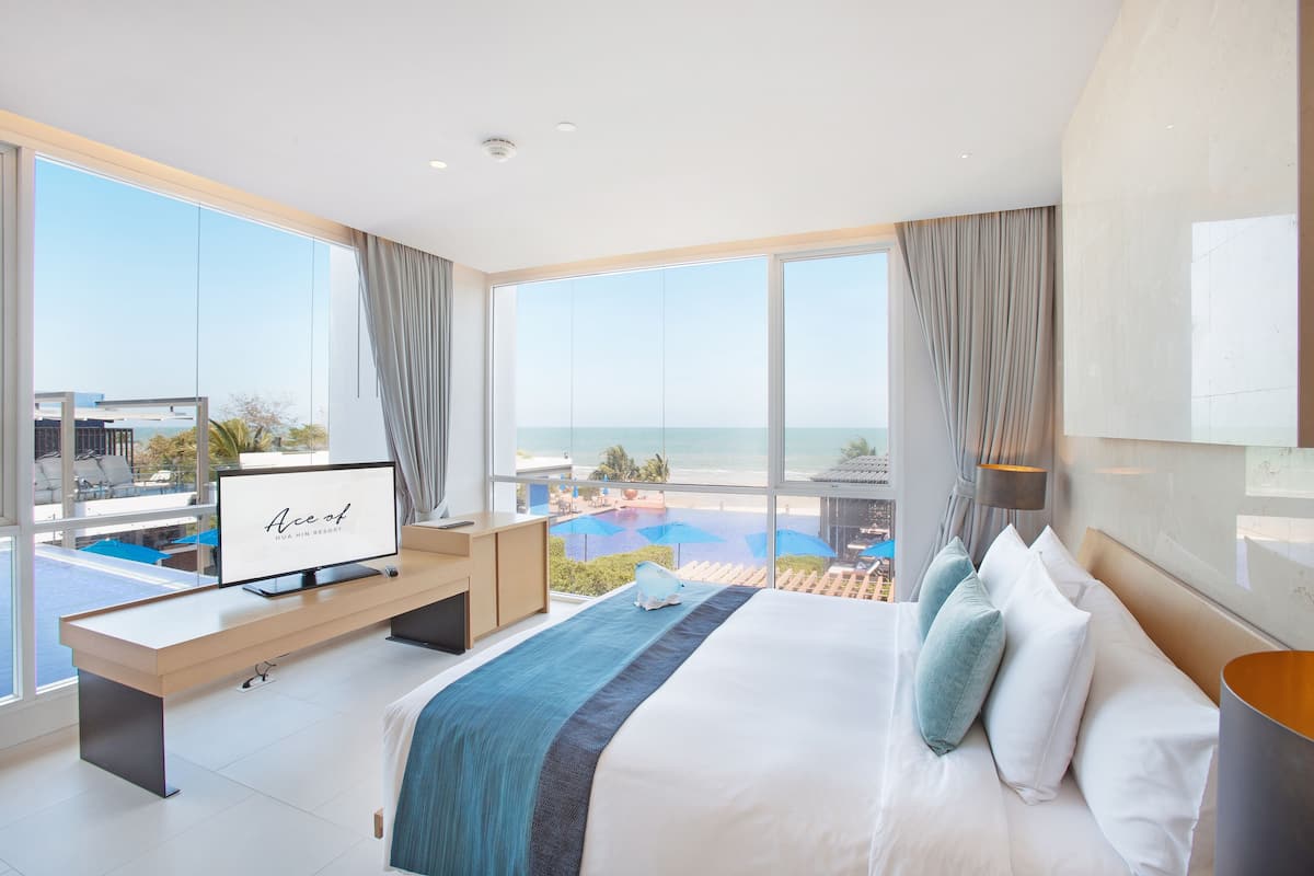 Ein modernes Hotelzimmer mit einem großen Bett, einem Schreibtisch und einem Fernseher, der "Ace of Hua Hin Resort" zeigt.