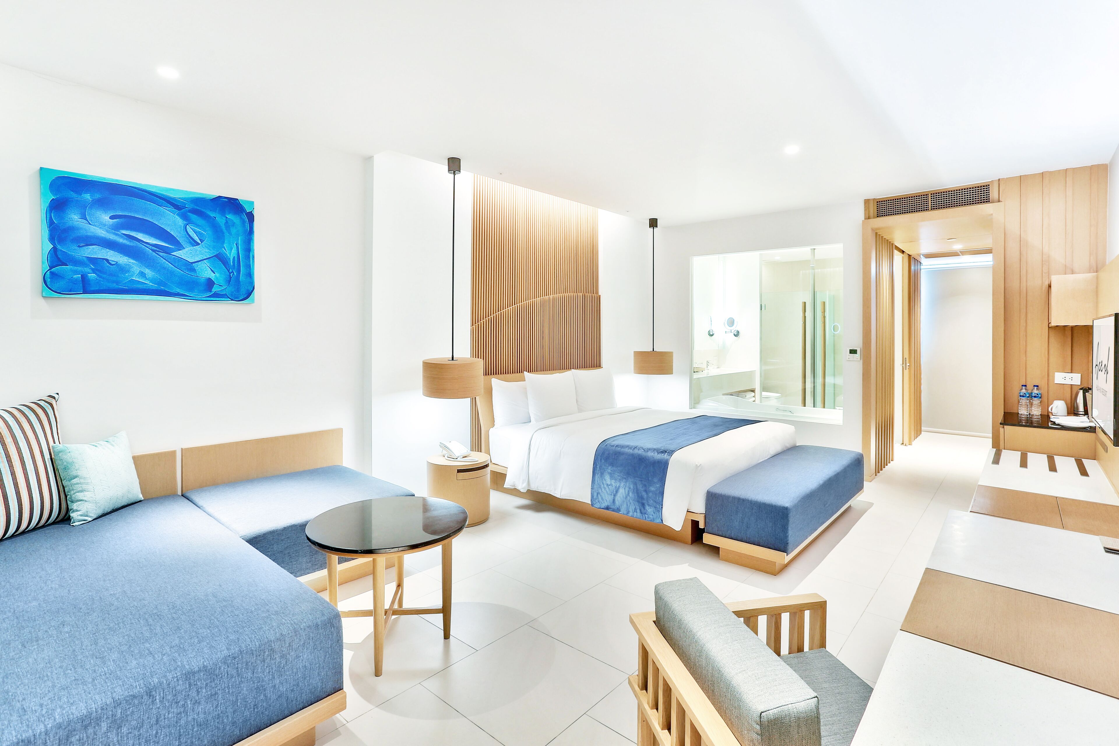 A modern hotel room with a large bed, a sofa, a small table, and a TV.