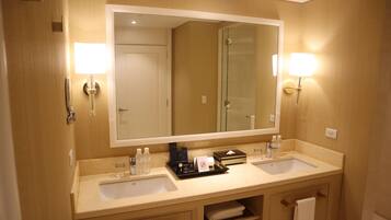 A hotel bathroom with two sinks, a large mirror, and wall-mounted lights.