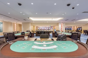 A casino floor with multiple blackjack tables, poker tables, and slot machines. - Royce Hotel & Casino (Mabalacat City)