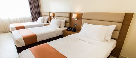 A hotel room with two beds, each with a headboard, bedside tables, and lamps.