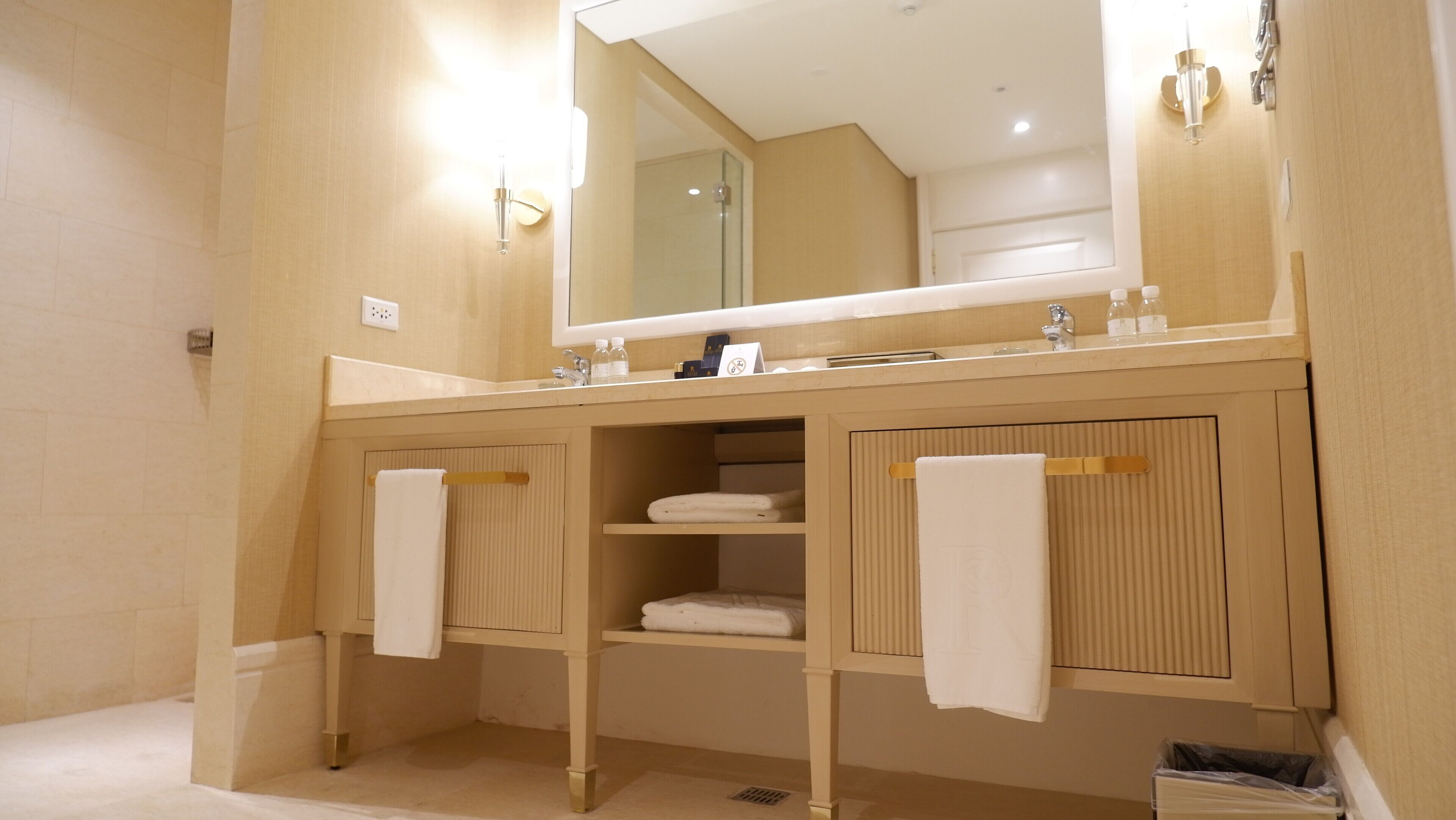 A modern bathroom with a large mirror, wooden cabinetry, and two towel racks.