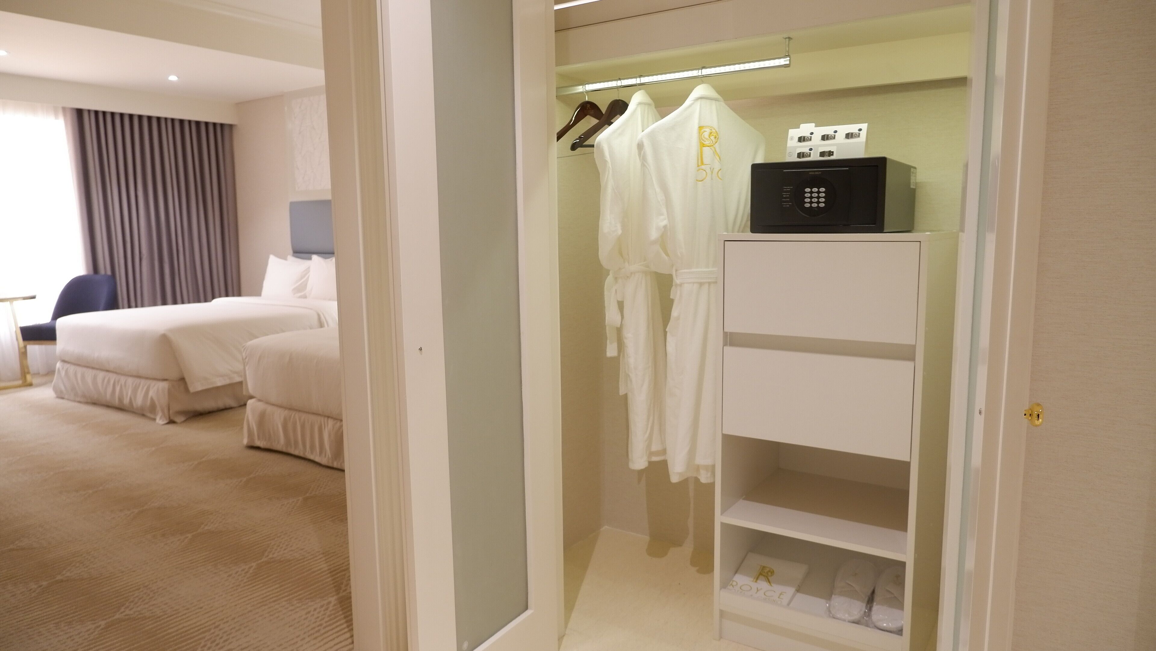 Ein Hotelzimmer mit Bett, Nachttisch, Sessel, Kleiderschrank mit Kleiderhaken und Schuhablage.