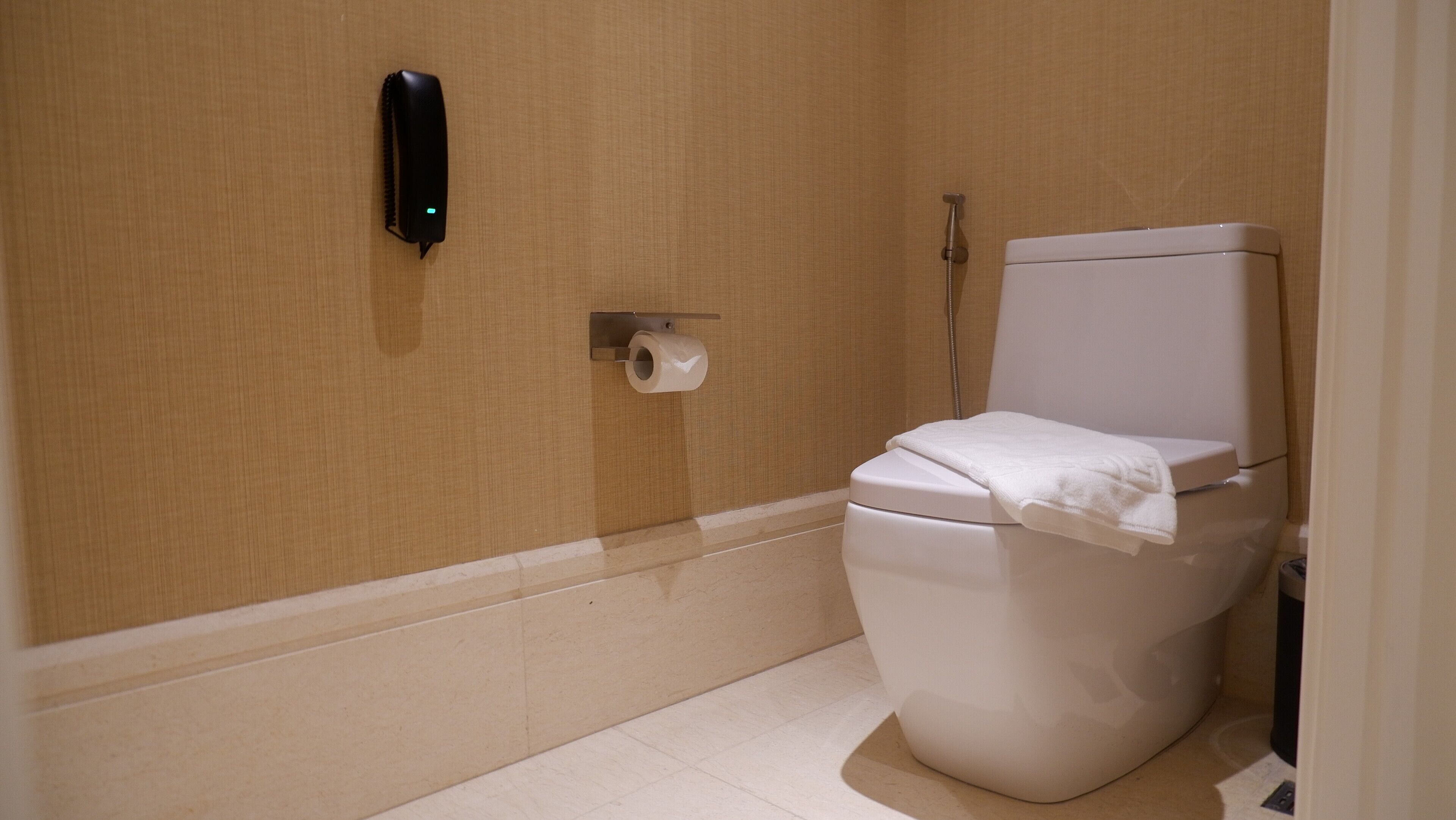Un baño con inodoro, dispensador de toallas de papel y cabezal de ducha.
