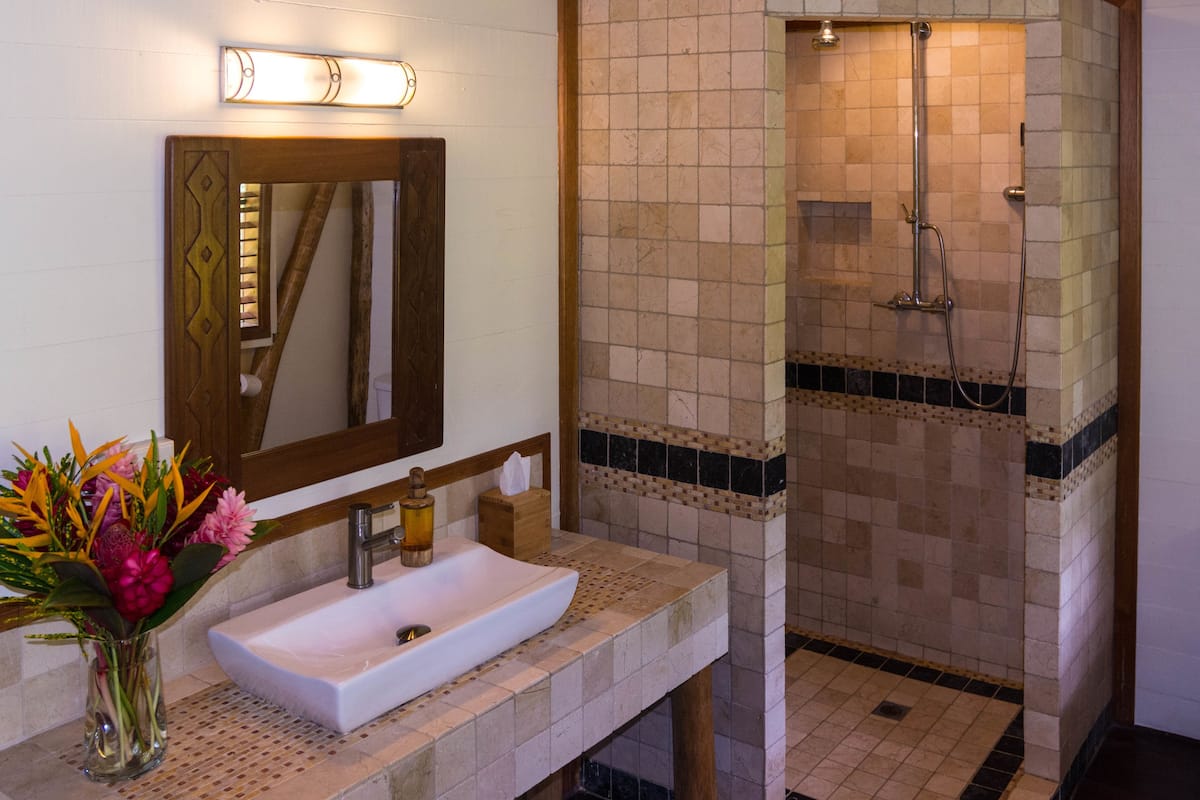 A bathroom with a white sink, a mirror, and a shower area with tiled walls.