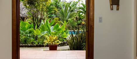 A bedroom with a view of a garden and a swimming pool.