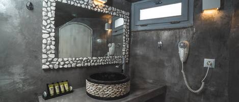 A bathroom with a stone sink, a mirror with a stone frame, a hairdryer, and a telephone.