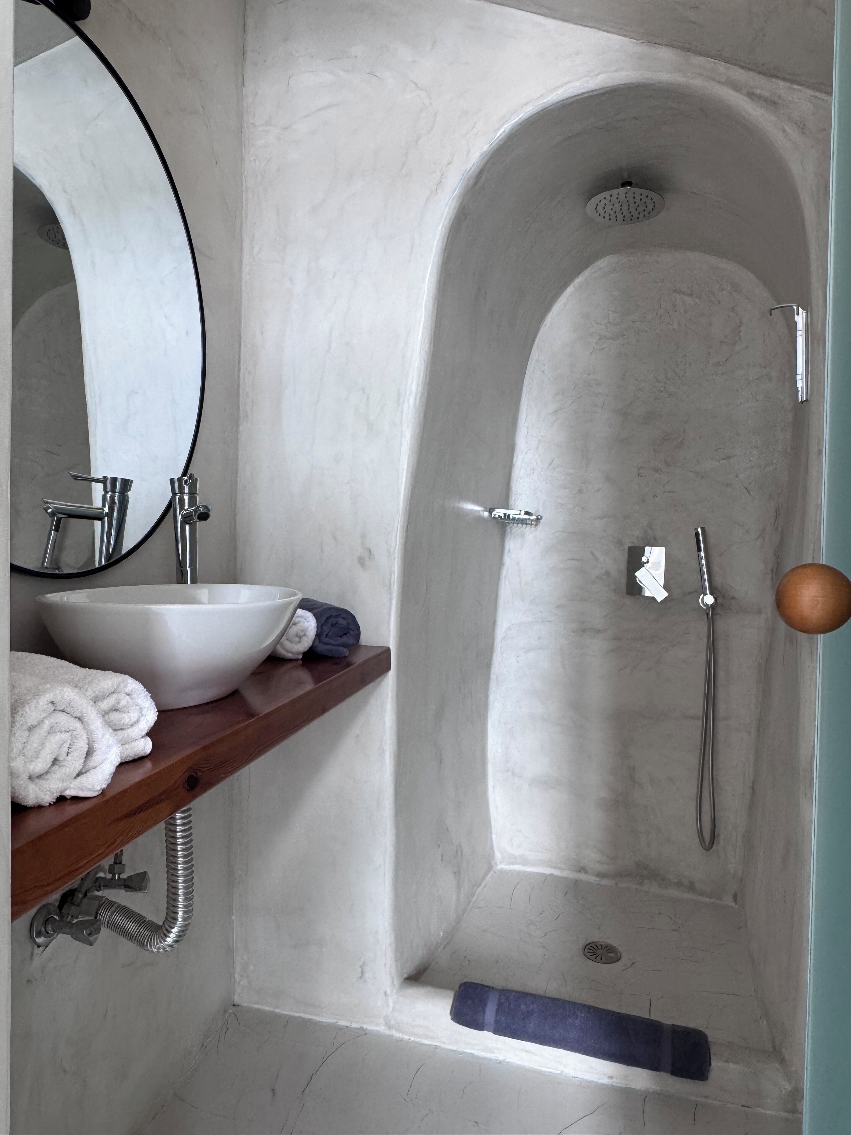 Un baño con una bañera independiente, un lavamanos con lavabo integrado y un estante de madera con toallas.