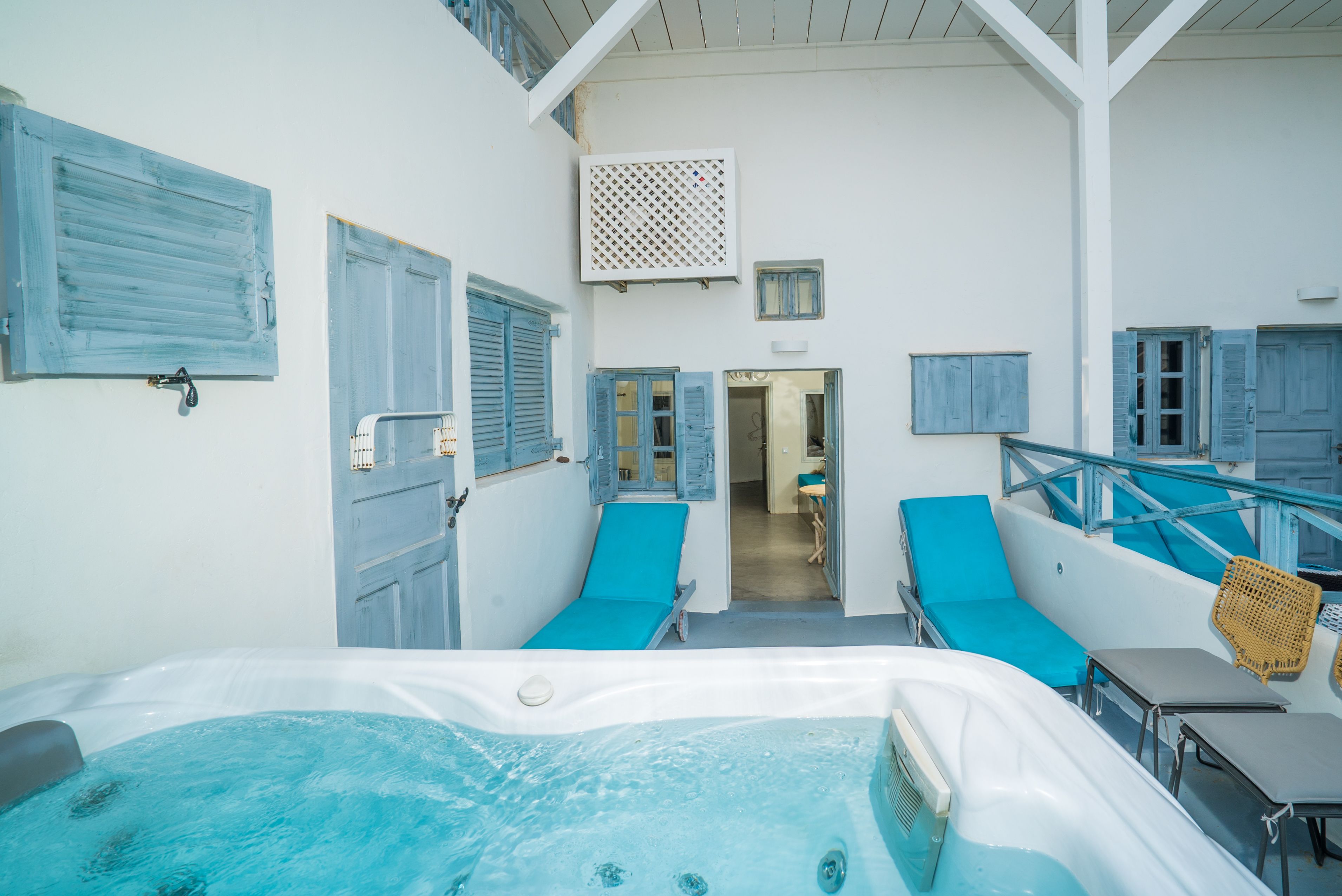 Un área de spa con una bañera de hidromasaje, sillones acolchados azules y vistas de la habitación contigua.