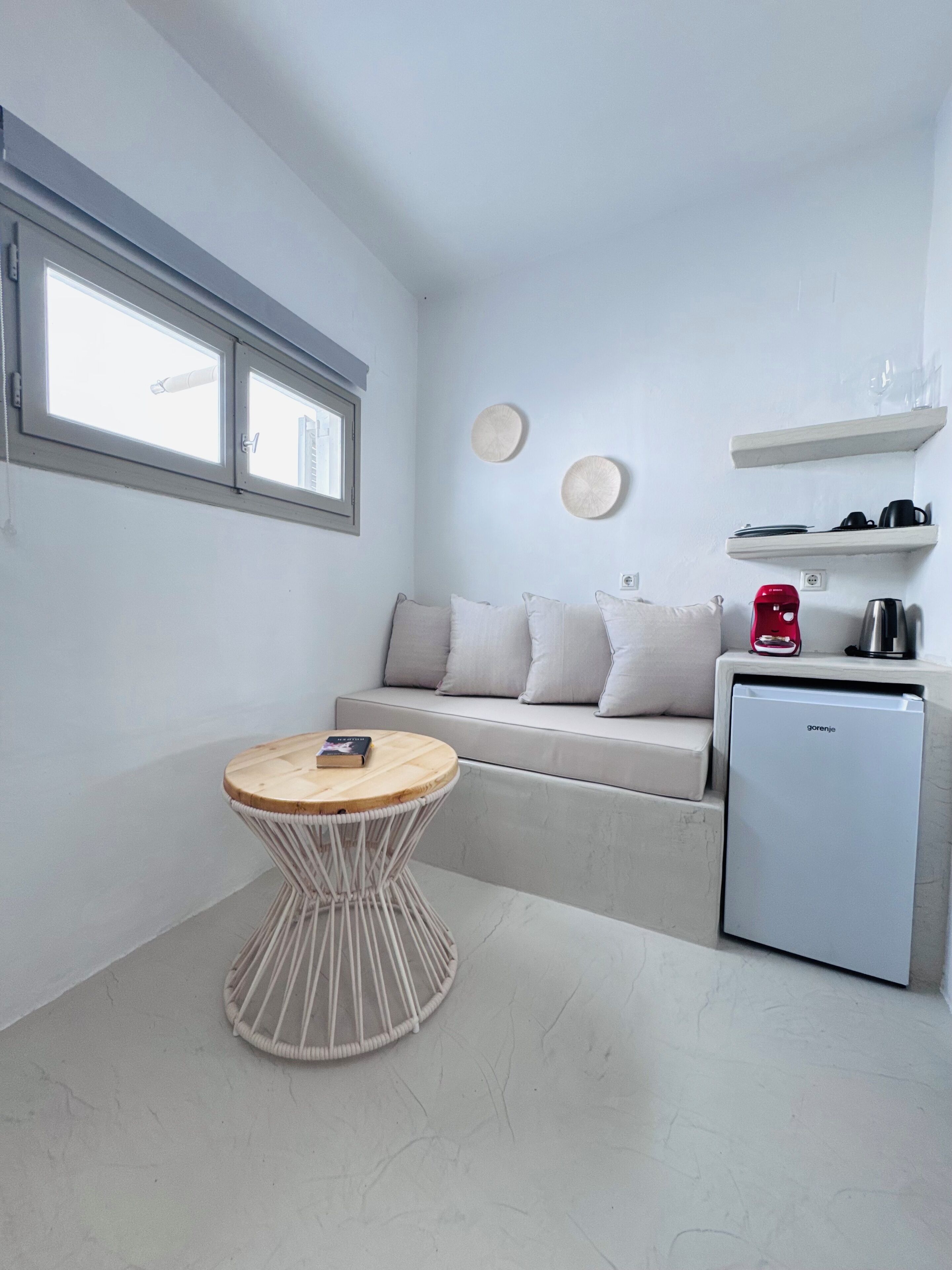 Una cocina compacta con refrigerador incluido, una pequeña mesa de comedor y un ventanal sobre el fregadero.