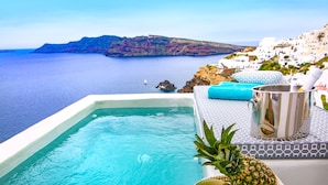 Une piscine avec vue sur la mer et un bâtiment blanc en arrière-plan.