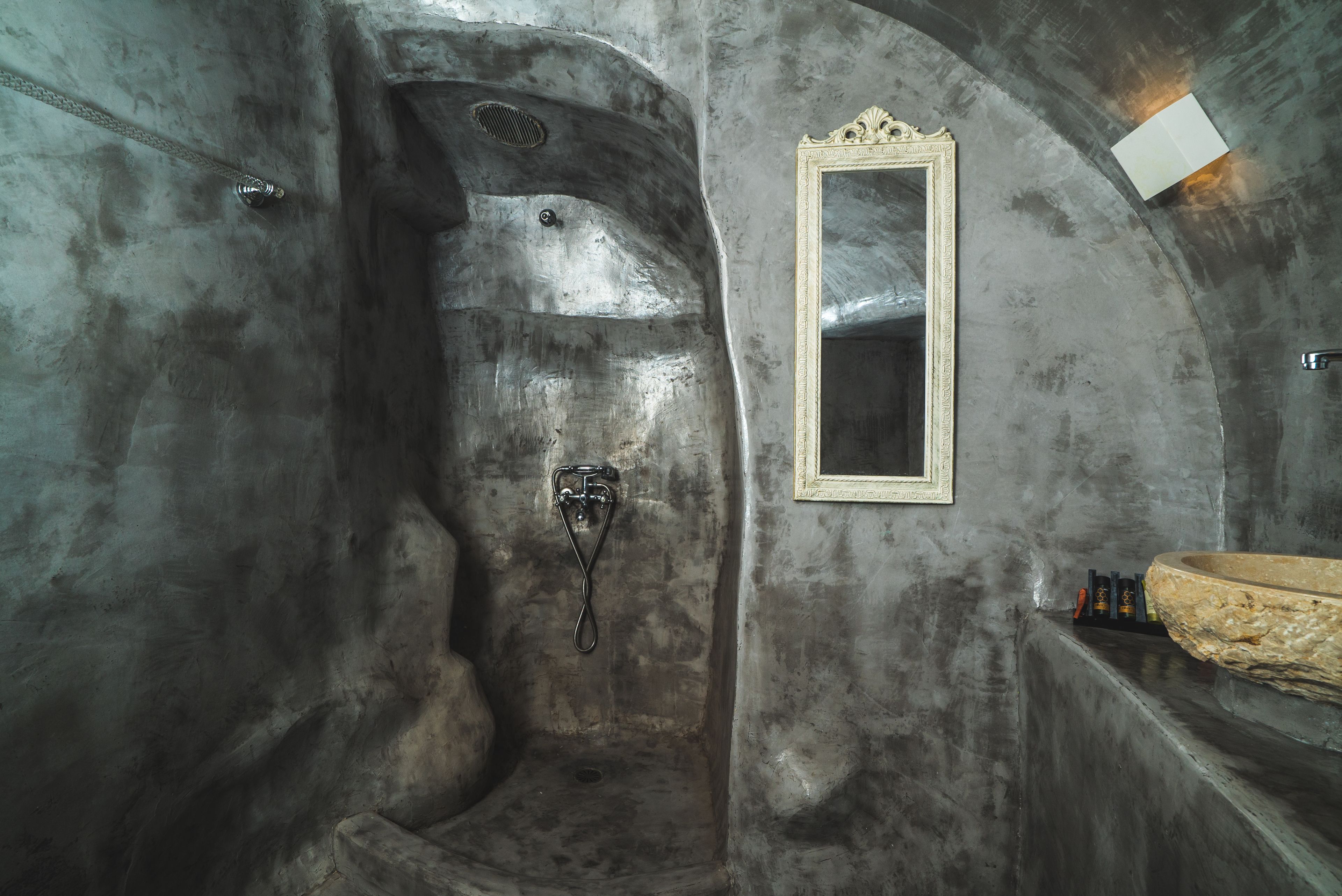 A bathroom with a large bathtub, a mirror, and a stone basin.
