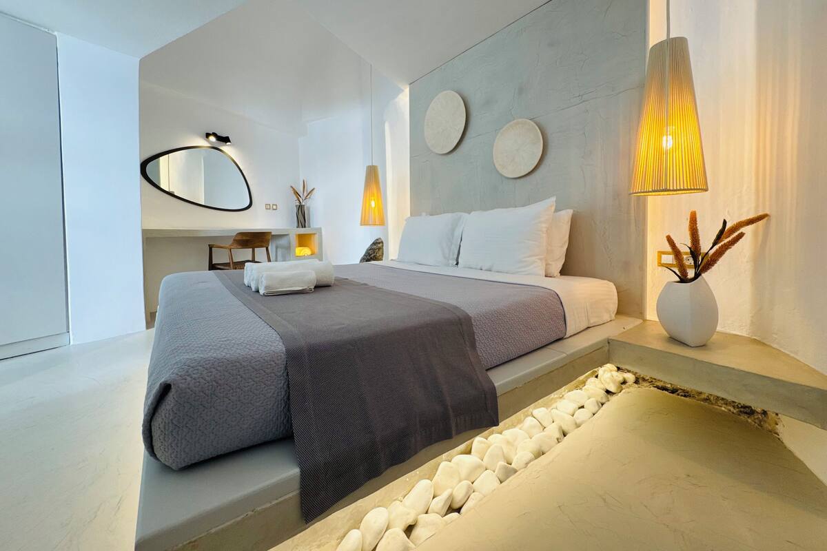 Een moderne slaapkamer met een bed, nachtkastjes, een bureau en een spiegel.