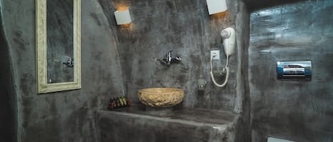 A bathroom with a large mirror, a stone sink, and a toilet.