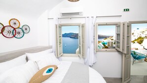 Une chambre à coucher avec un lit, une vue sur la mer et une fenêtre donnant sur un bâtiment blanc.