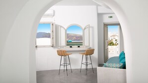 Une pièce avec deux fauteuils en osier, une fenêtre donnant sur les montagnes et un mur blanc.