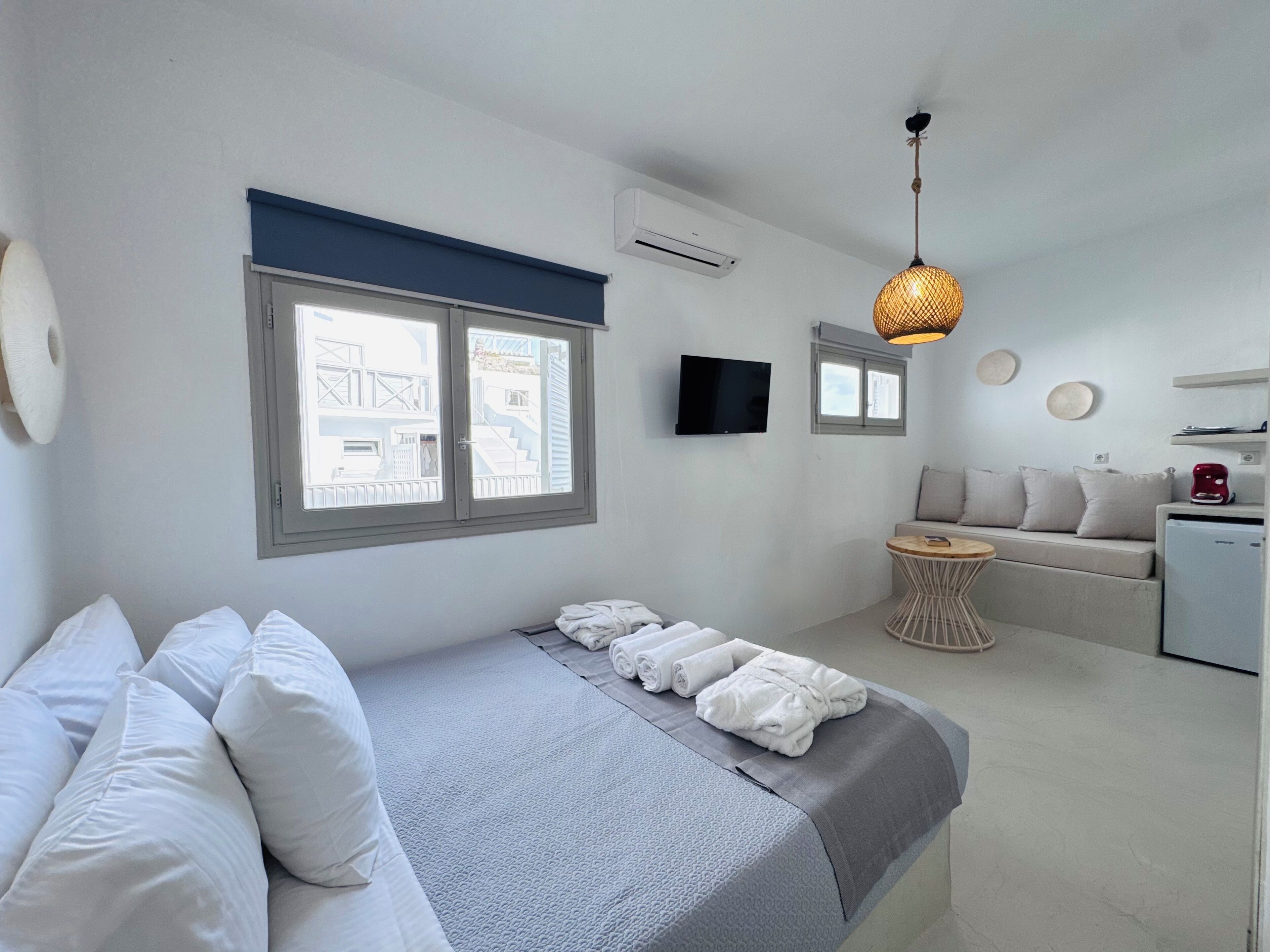 A modern bedroom with a bed, a TV, a sofa, and a small table.