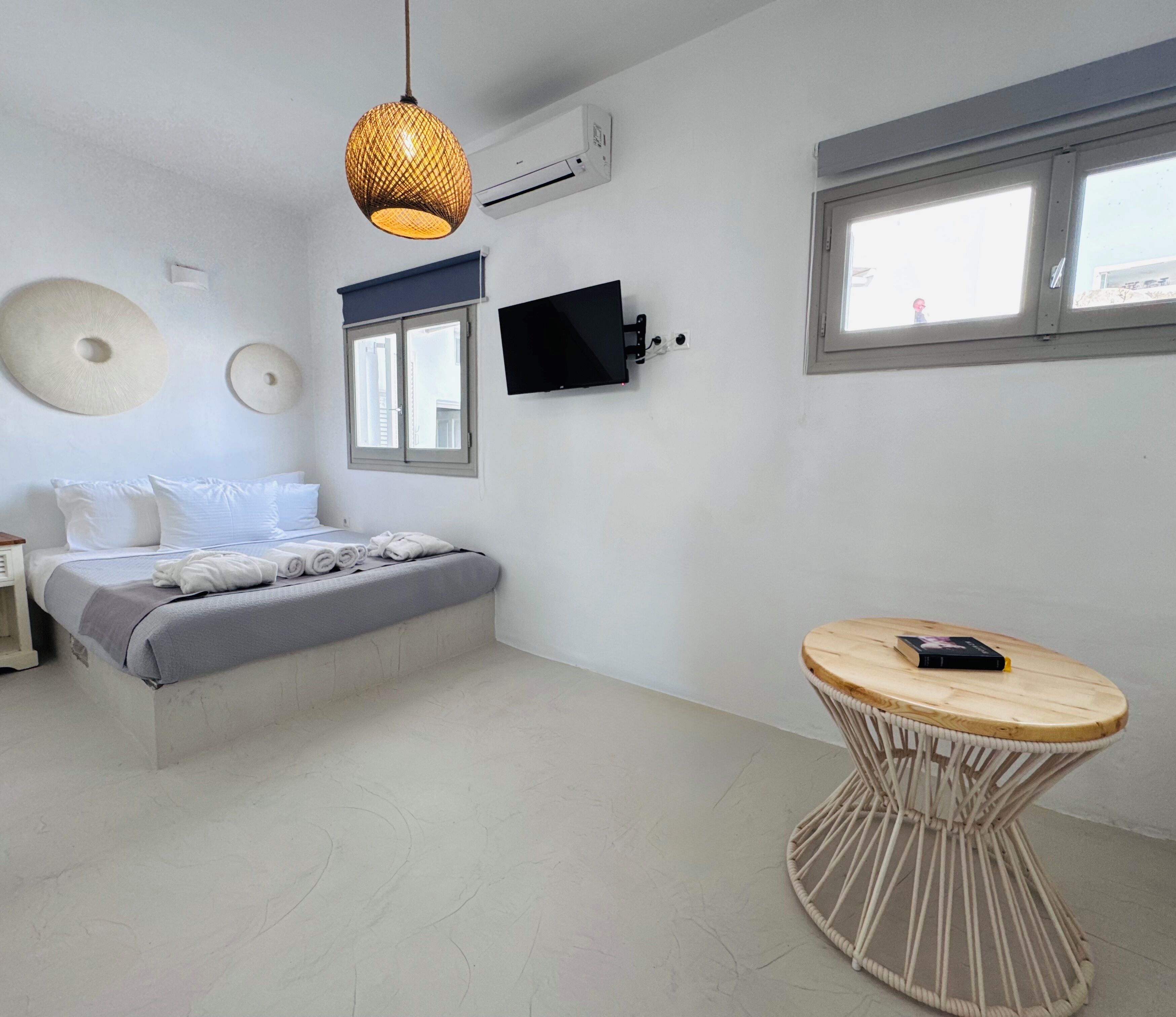 Een moderne slaapkamer met een bed, een rond tafeltje en een televisie.