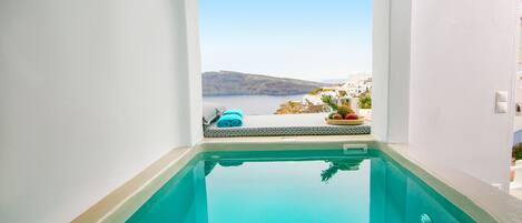 A clear view of a swimming pool with a view of the sea and distant hills.