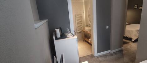 A compact room with a desk, a bed, and a bathroom.