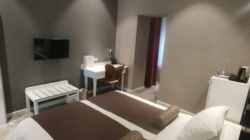 A hotel room with two beds, a desk, a chair, a TV, and a window with curtains.