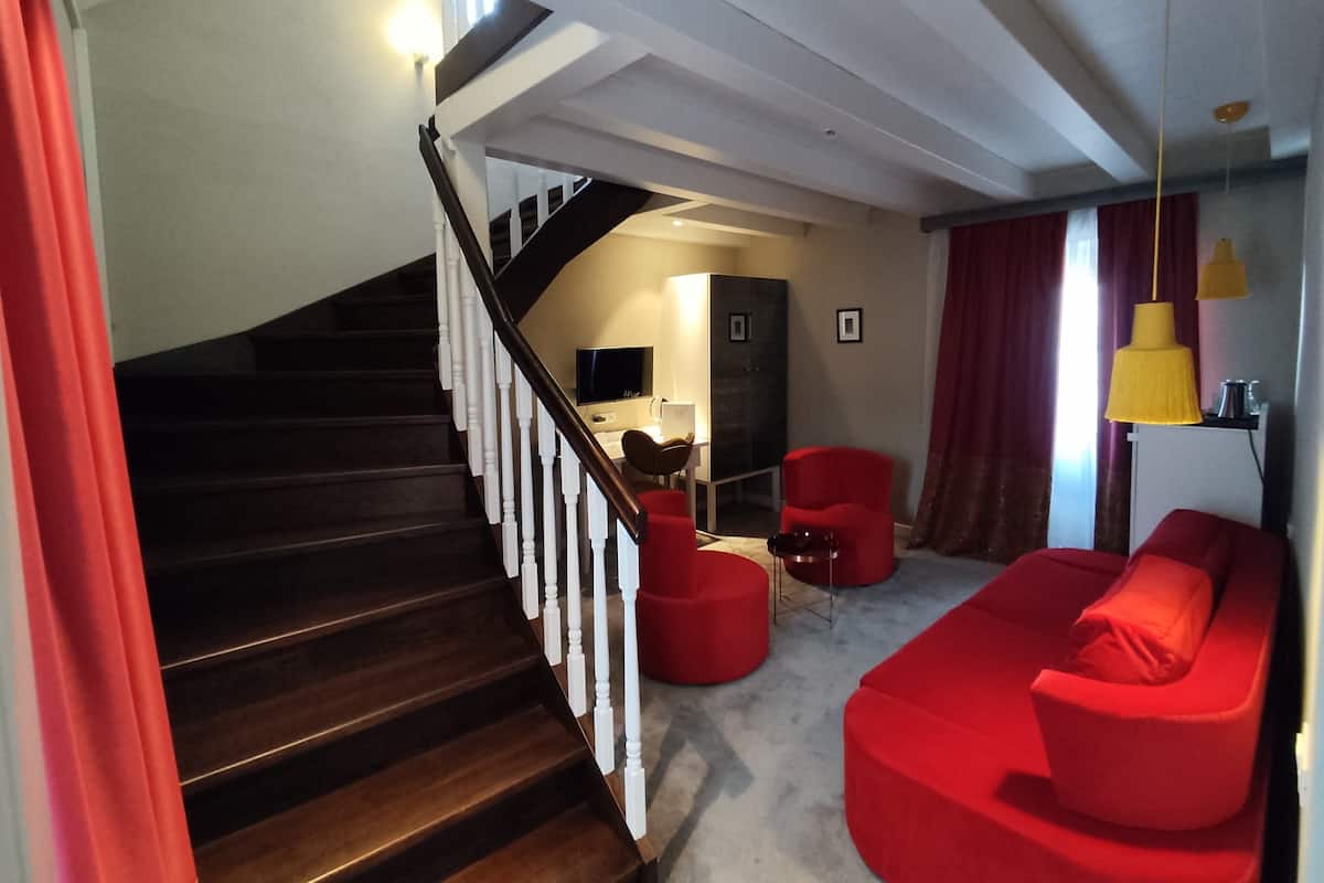 A modern living room with a staircase, red furniture, and a flat-screen TV.