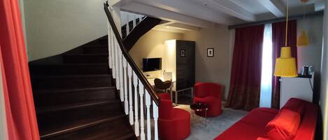 Un salon moderne avec un escalier, des meubles rouges et un téléviseur à écran plat.