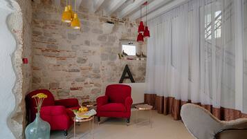 Una sala de estar acogedora con pared de piedra, sillones rojos, una mesita de centro y luces colgantes.