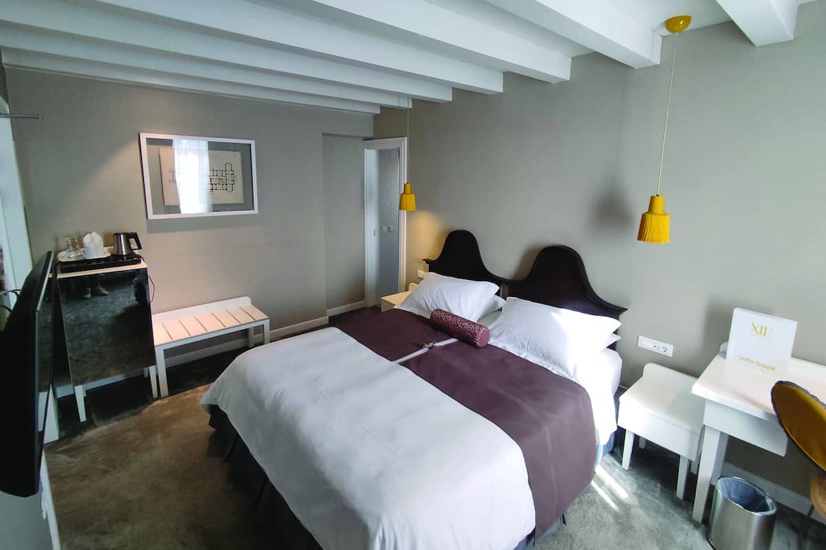A hotel room with a bed, bedside table, desk, and a small seating area.