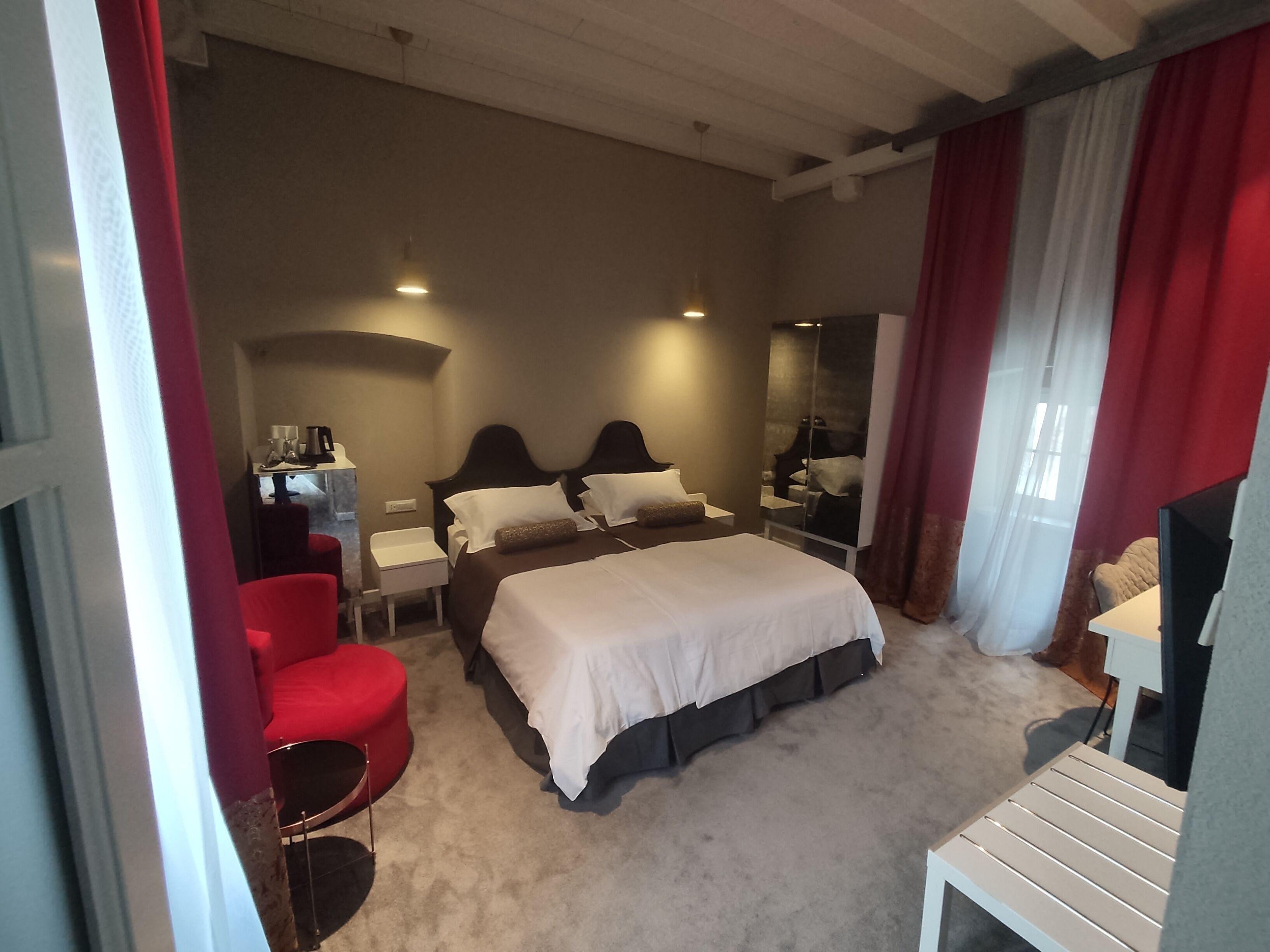 Una camera d'albergo con un letto grande, una scrivania, una sedia e uno specchio.