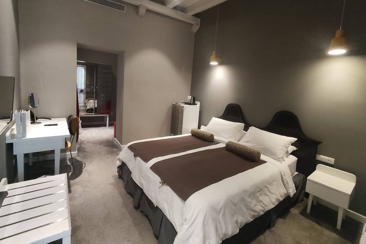 A modern bedroom with a large bed, bedside tables, a desk, and a chair.