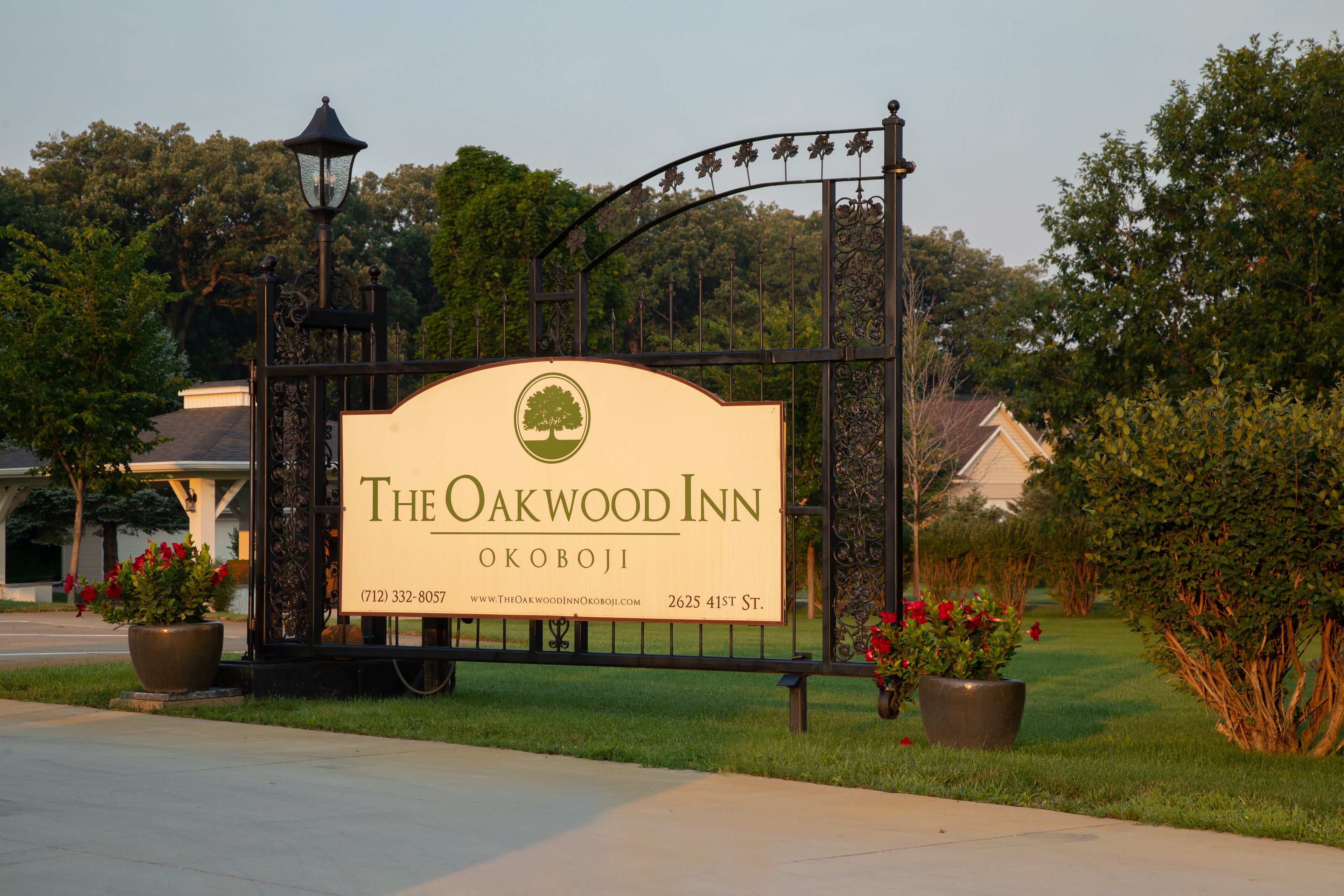 Une enseigne pour l’hôtel The Oakwood Inn, avec un logo représentant un arbre, un numéro de téléphone et l’adresse du site web.