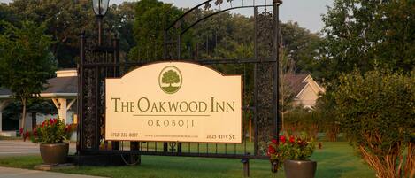 Letrero de The Oakwood Inn con logotipo de árbol, número de contacto y URL del sitio web.