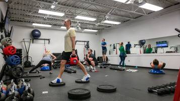 Une salle de sport équipée de divers appareils d’entraînement, notamment des kettlebells, des haltères et des ballons d’exercice.