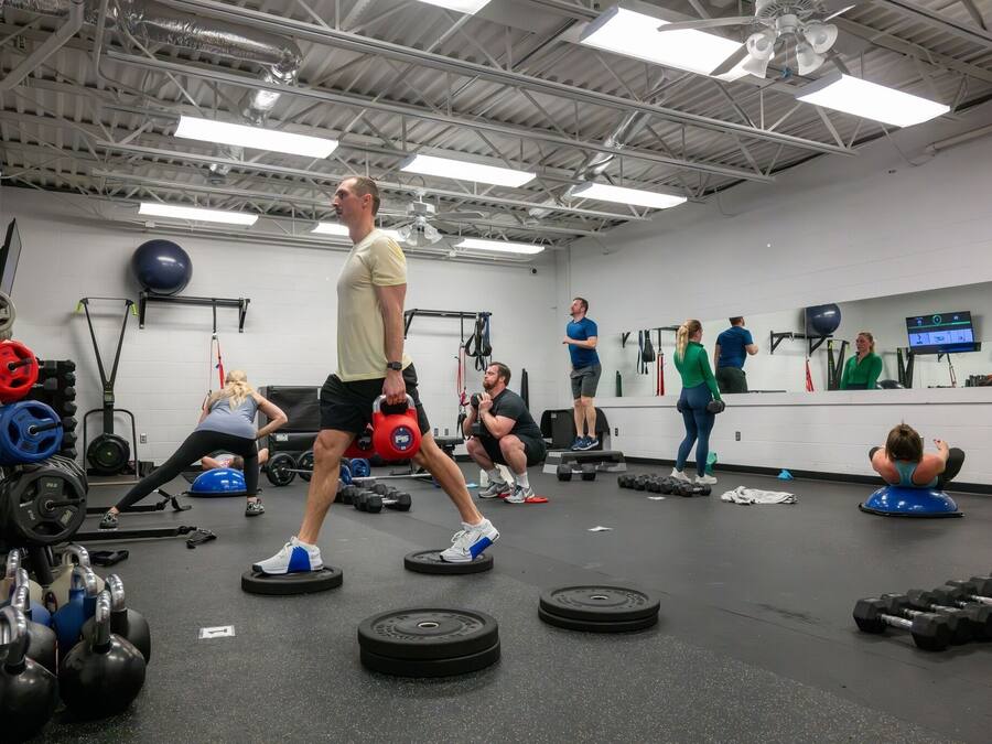 Une salle de sport équipée de divers appareils d’entraînement, notamment des kettlebells, des haltères et des ballons d’exercice.